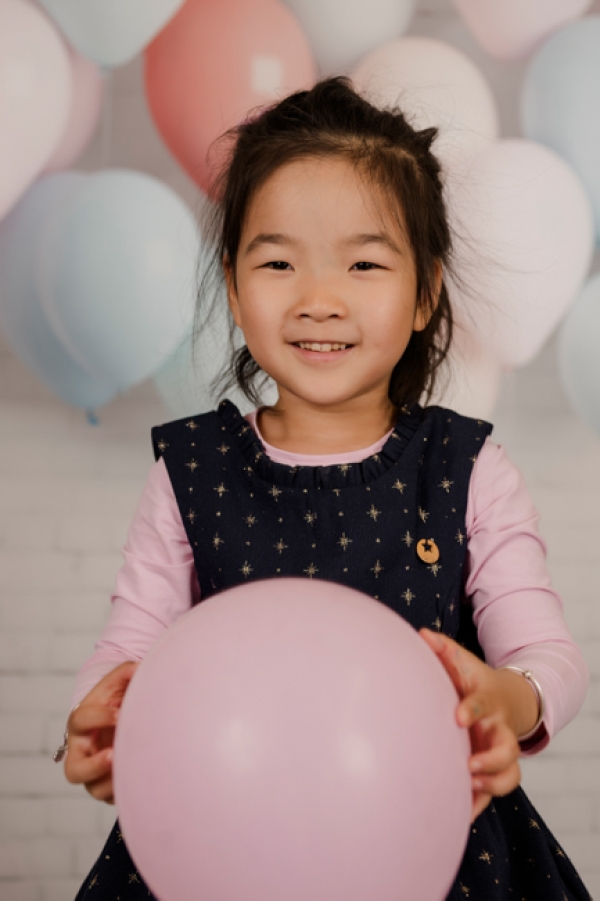 Fröhliches Kindergartenfoto eines Mädchens mit rosa Ballon