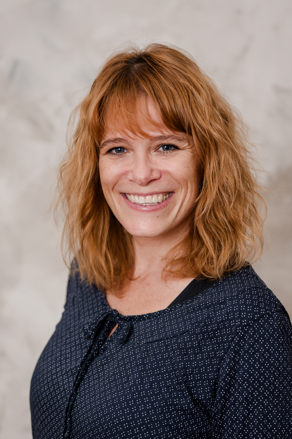 Miriam und Anna sitzen lachend auf einer Mauer.