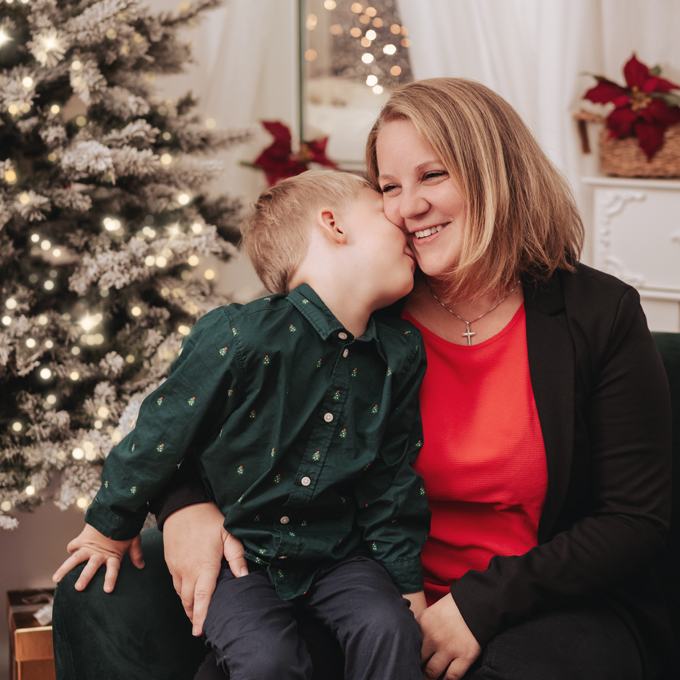 Weihnachtsfoto einer Mutter mit ihrem Sohn, vor einem Weihnachtsbaum kuschelnd