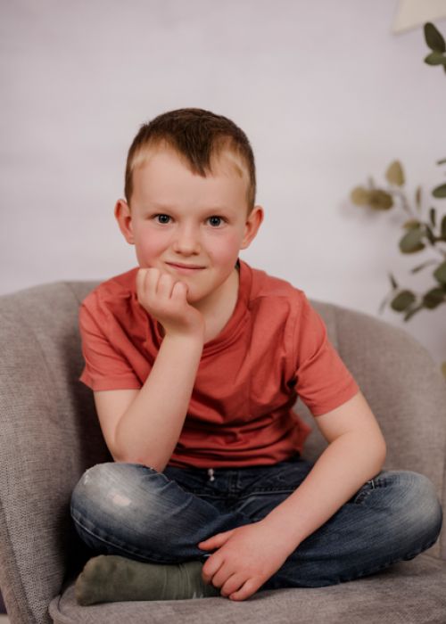 Miriam und Anna sitzen lachend auf einer Mauer.